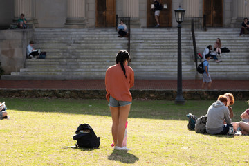 A college girl picks out a spot to lay out on the campus with fellow students