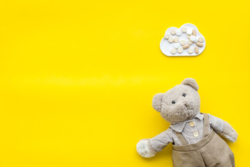 Childhood diseases concept. Treatment of children.Teddy bear toy and pills on yellow background top view space for text