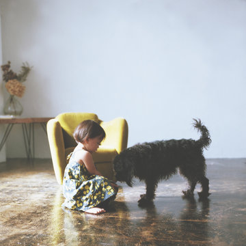 Side view of girl with dog sitting on floor at home