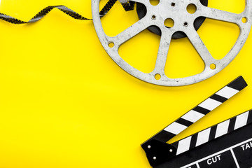 Filmings concept. Clapperboard and film stock on yellow background top view space for text