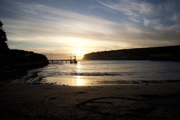 Naklejka premium sunset skies across the beach amid cliffs