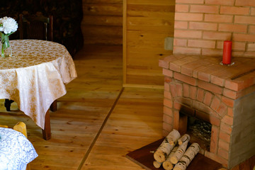 room in a rustic wooden house with fireplace, table and vase with flowers - obrazy, fototapety, plakaty