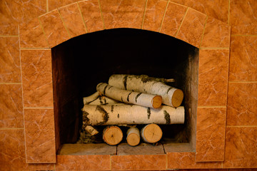 fireplace, decorated with tiles, with birch firewood