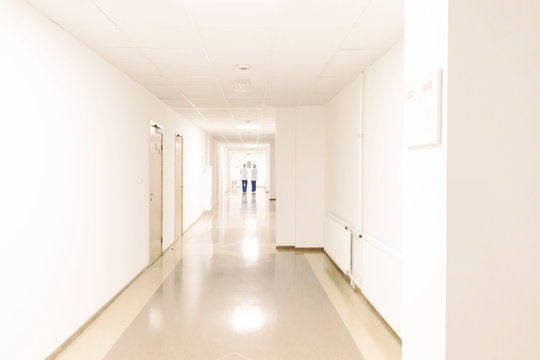White clean corridor in scientific research lab, medical center. Two unrecognizable women.