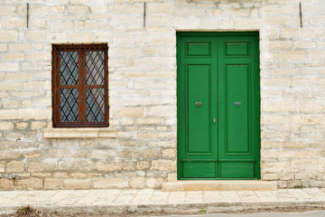 Fototapeta na wymiar Architecture details from the Renaissance - green painted wooden door and window with a grate of a stone house in Kavarna city, Bulgaria