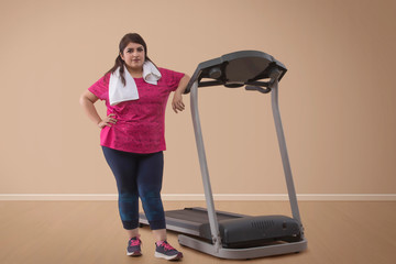 Fototapeta na wymiar Portrait of Overweight woman standing with treadmill 