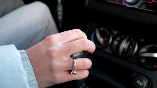 close view in car cabin girl hand with red manicure and ring shifts gears in auto driving automobile carefully