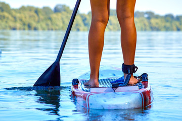 Close-up of a woman legs on stand up paddle in water