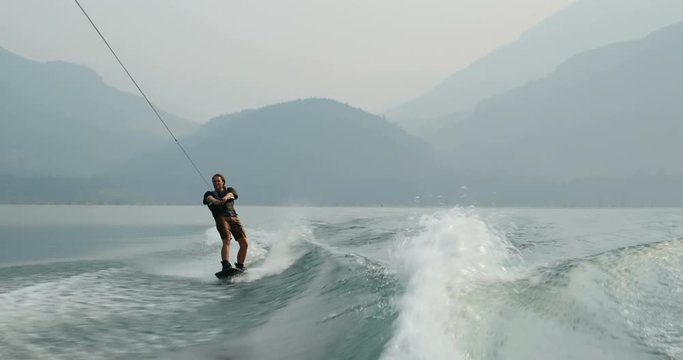 Front view of caucasian young man doing tricks on wakeboard in the city river 4k