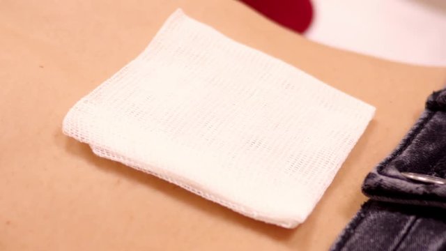 closeup slow motion large white cotton napkin lies on girl belly near jeans belt after piercing 