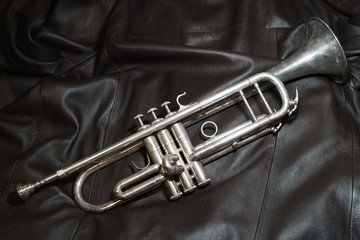 Image of a trumpet lying on a brown leather jacket © Yury and Tanya
