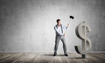 Determined banker man in empty concrete room breaking dollar figure