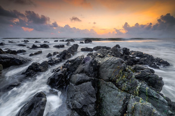 A scenery of sunrise with amazing unique rock formation and beautiful  flow of wave at Kemasik beach, Terangganu Malaysia. Soft focus during long exposure shot.