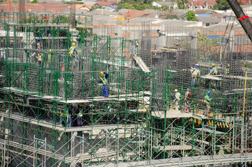 Asian people and thai workers with heavy machinery working builder new building at construction site high-rise building on scaffold at Bangkok, Thailand.