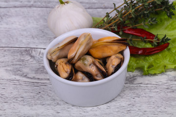Pickled mussels in the bowl served pepper, garlic and salad