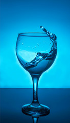 glass of splash water on blue background