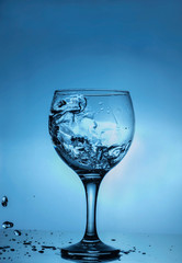 glass of splash water blue background