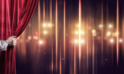 Bokeh lights behind drapery curtain and hand opening it
