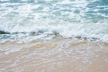 White foam waves of the sea on the sand by the beach