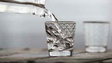 Alcohol flow in a glass with ice. Vodka pouring