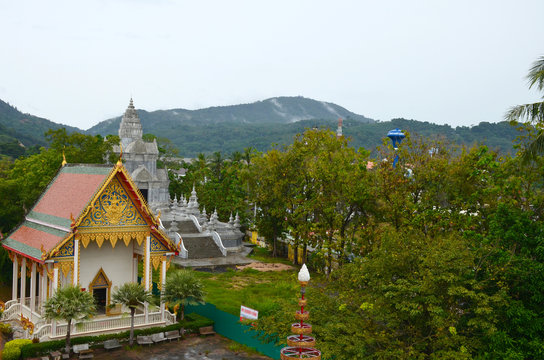 Wat Chalong Temple, Phuket, Thailand. Top view on pagoda and buildings of temple on the background of green mountains.