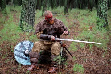 Real viking sharpening his sword with a stone