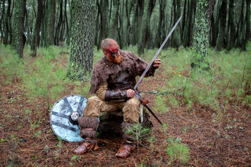 Real viking sharpening his sword with a stone