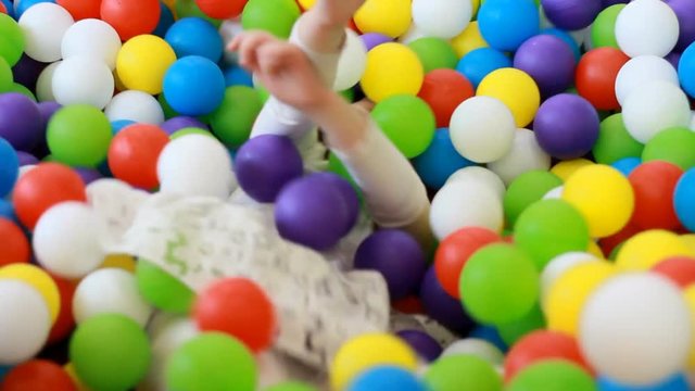 Happy child girl playing and hiding on the playground with multicolored balloons