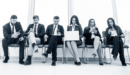 business team looking for information on the Internet using a smartphone and laptop sitting in the lobby of the modern office