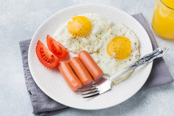 Fried eggs and sausage, tomatoes on a plate. concept breakfast