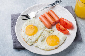 Fried eggs and sausage, tomatoes on a plate. concept breakfast