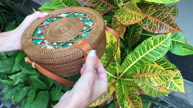 Closeup of stylish handmade rattan handbag on a tropical background. Bali island.