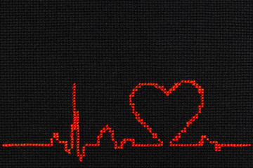 Cardiogram with a heart symbol is embroidered with red thread on a black cloth.