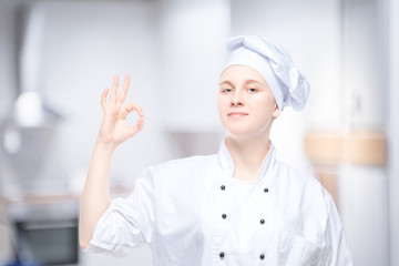 female chef showing hand gesture, satisfied portrait on the background of the kitchen