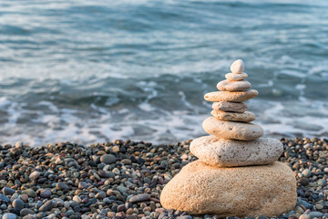 Fototapeta na wymiar Pyramid of white stones on a pebble beach close-up concept photo balance
