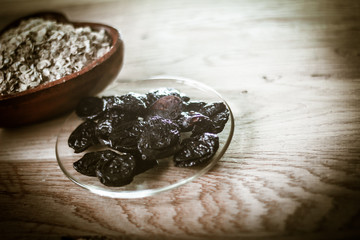 prunes in a bowl and cereal on a wooden table