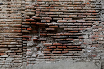 Old crumbling brick wall with fallen bricks