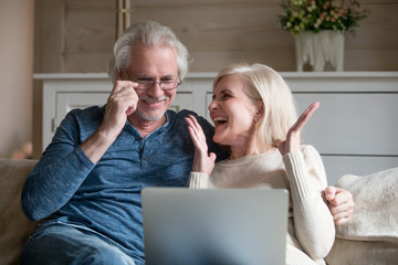Spouses sitting on couch feels happy received great news online - obrazy, fototapety, plakaty