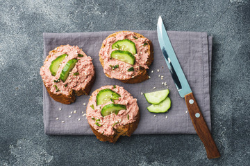 Sandwiches with chicken pate and cucumber on dark table.