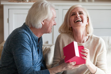 Spouses celebrating anniversary sitting in living room at home