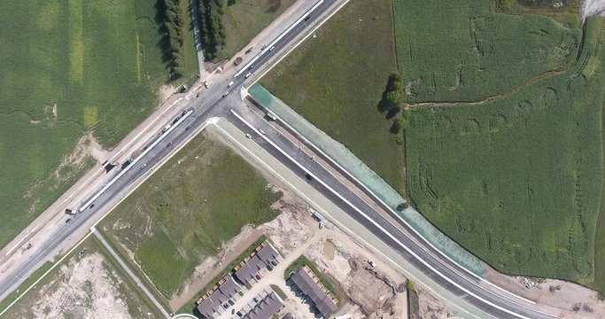Traffic Intersection Fly Over with Building Structures and Green Farm Fields