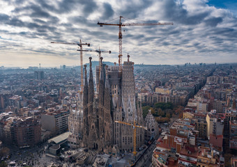 Fototapeta premium Aerial; drone view of main Gaudi project Sagrada Familia Temple; majestic building towering over the rooftops of Eixample district; long construction of the temple 