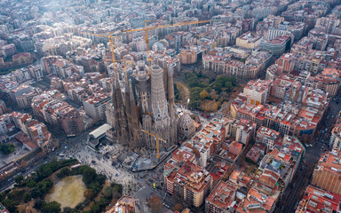 Aerial; drone view of main Gaudi project Sagrada Familia Temple; majestic building towering over the rooftops of Eixample district; one of the famous attraction for tourists and travelers in Barcelona
