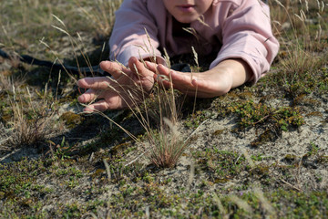 Woman lies on the ground and touches the grass with her hands, intimacy with nature