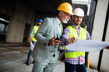 Confident team of architects and engineers working together on construction site