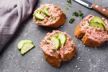 Sandwiches with chicken pate and cucumber on dark table.