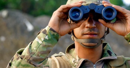 Front view of young caucasian military soldier observing on field during military training 4k
