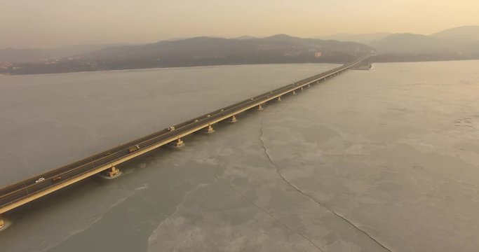 Landscape with a field of ice of the Amur Bay and the bridge Sedanka-De Vries. Vladivostok, Russia