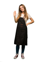 Full body Young woman with apron saluting with hand with happy expression on isolated background