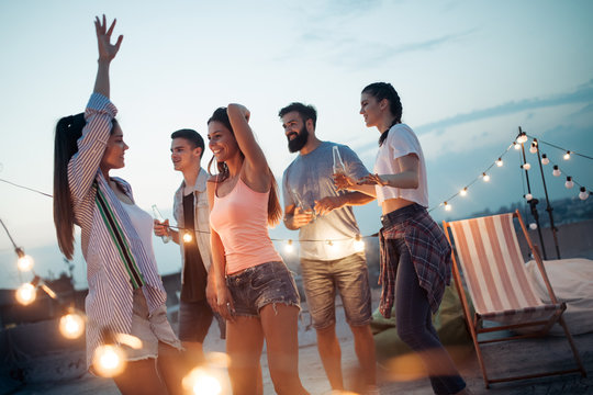 Carefree Group Of Happy Friends Enjoying Party On Rooftop Terrace